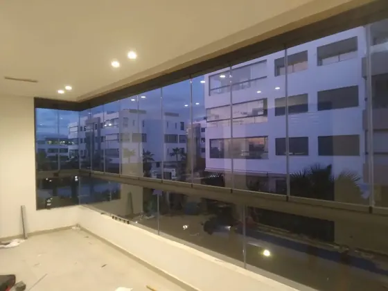 Baie vitrée panoramique d’angle ouvrant sur un balcon, appartement à Marrakech