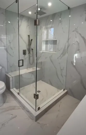 Cabine de douche d’angle en verre avec porte pivotante et marbre blanc