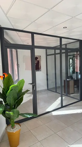 Cloison vitrée à cadre aluminium et porte battante à l’entrée d’un bureau