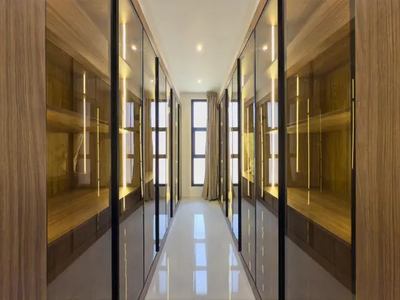 Couloir de dressing aux portes coulissantes aluminium, verre bronze et décor bois