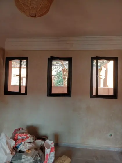 Trois fenêtres aluminium noires posées dans un mur en tadelakt