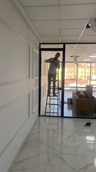 Pose d’une cloison vitrée à cadre noir dans un couloir de bureaux