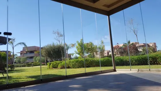 Angle vitré d’une véranda en aluminium donnant sur une pelouse
