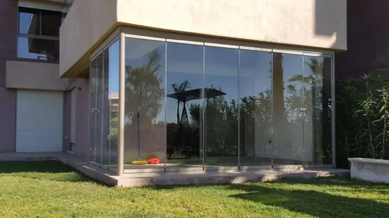 Véranda vitrée d’angle en aluminium sur un jardin engazonné