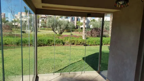 Vue depuis l’intérieur d’une véranda en verre sur le jardin et les oliviers