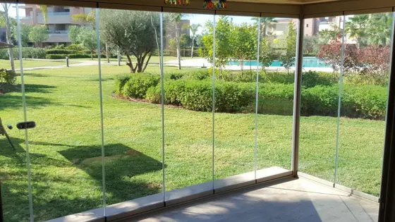 Véranda vitrée avec vue sur le jardin et la piscine d’une résidence
